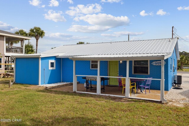 back of house featuring a lawn, central AC, metal roof, and a patio area