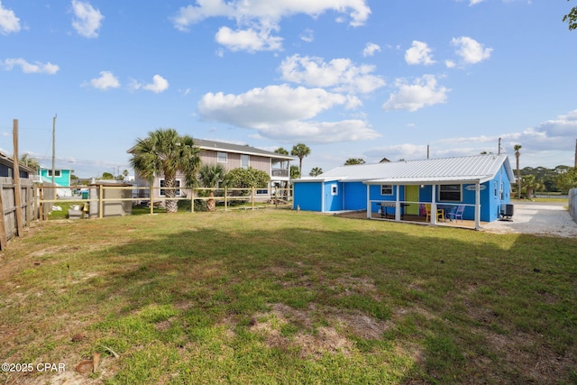 rear view of property featuring a lawn, cooling unit, metal roof, and fence private yard