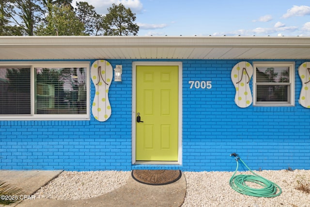 view of exterior entry featuring brick siding
