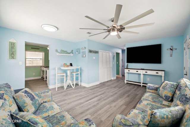 living area with baseboards, ceiling fan, and wood finished floors