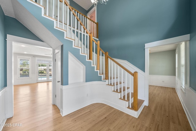 stairs featuring a wainscoted wall, wood finished floors, and a high ceiling
