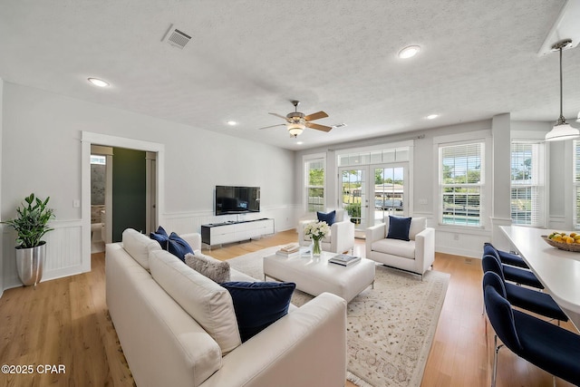 living area with a wainscoted wall, light wood-type flooring, visible vents, recessed lighting, and ceiling fan