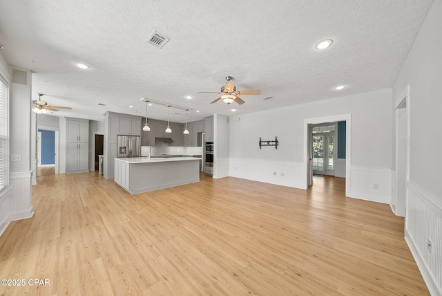 unfurnished living room featuring recessed lighting, a textured ceiling, a ceiling fan, and light wood-type flooring