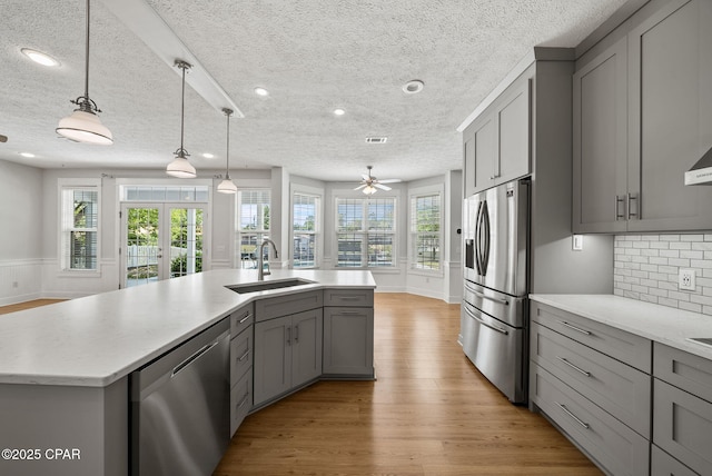 kitchen featuring a sink, a textured ceiling, gray cabinets, and appliances with stainless steel finishes