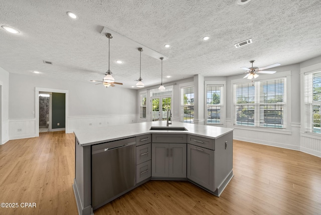 kitchen with a ceiling fan, gray cabinetry, stainless steel dishwasher, visible vents, and a sink