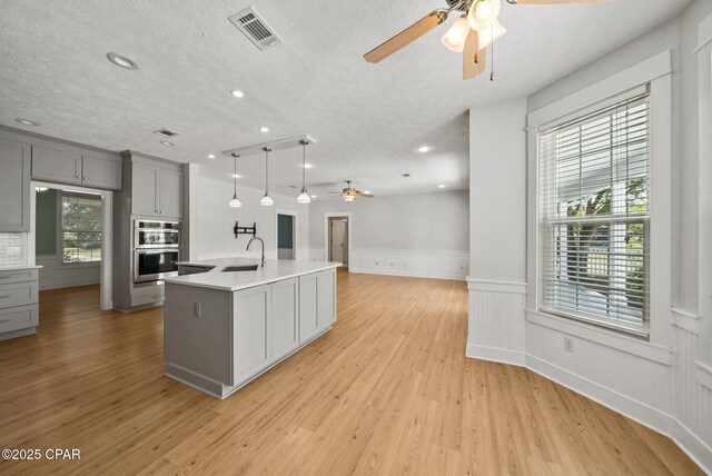 kitchen featuring double oven, gray cabinets, visible vents, and ceiling fan