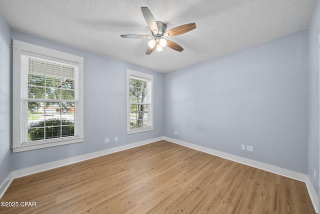 empty room with ceiling fan, a textured ceiling, baseboards, and wood finished floors