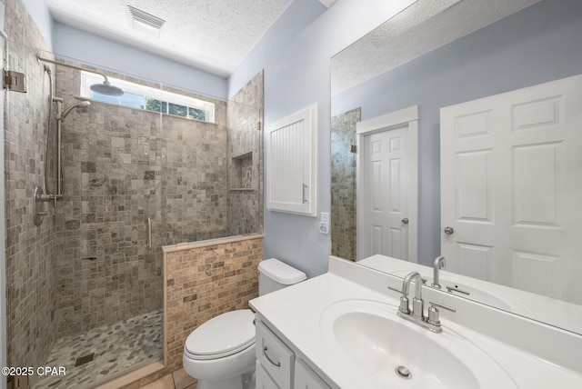 bathroom with toilet, vanity, a textured ceiling, visible vents, and a tile shower