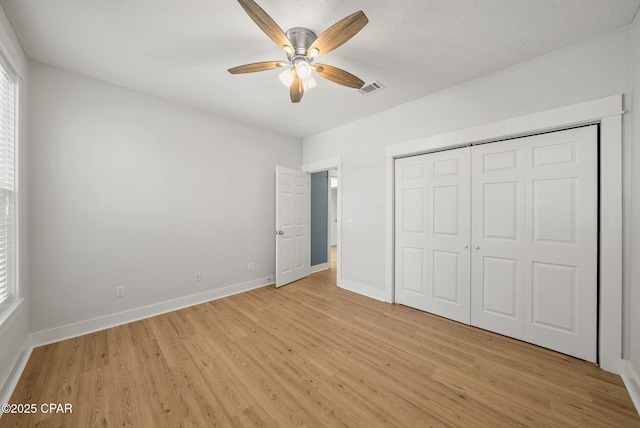 unfurnished bedroom featuring a closet, light wood-type flooring, visible vents, ceiling fan, and baseboards