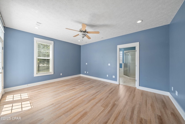 unfurnished bedroom with a textured ceiling, light wood-style flooring, and baseboards