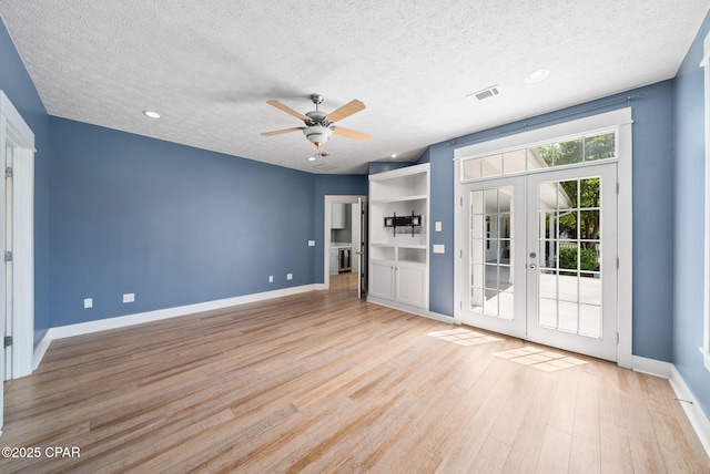 interior space featuring a ceiling fan, french doors, a textured ceiling, baseboards, and light wood-style floors
