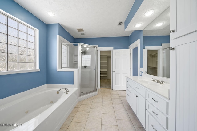 bathroom featuring a stall shower, a walk in closet, a textured ceiling, visible vents, and vanity