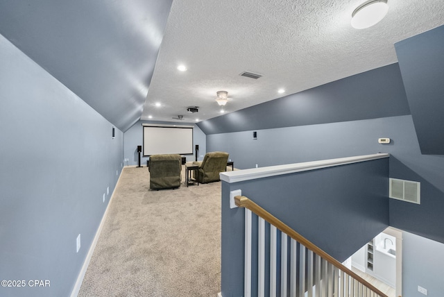 cinema room featuring carpet, visible vents, baseboards, and lofted ceiling