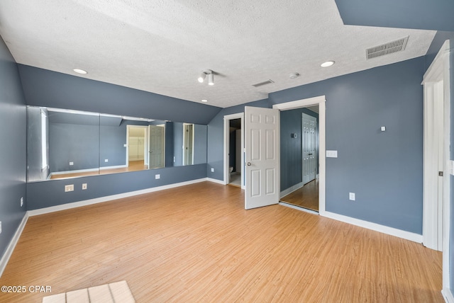 interior space featuring a textured ceiling, baseboards, visible vents, and wood finished floors