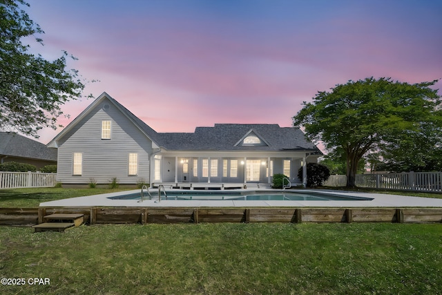 rear view of property with fence private yard, a fenced in pool, and a lawn