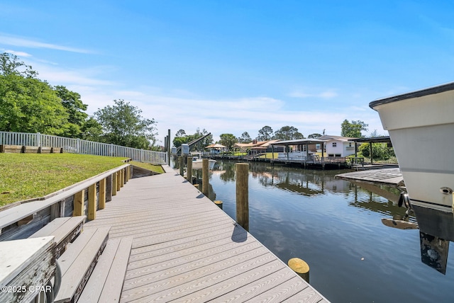 view of dock featuring a water view, fence, and a lawn