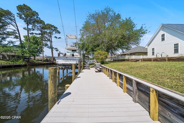 dock area with a water view, boat lift, and a lawn