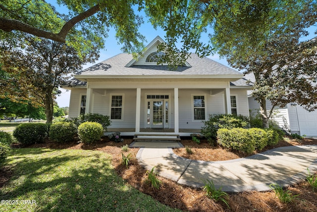 view of front of home with covered porch, roof with shingles, and a front yard