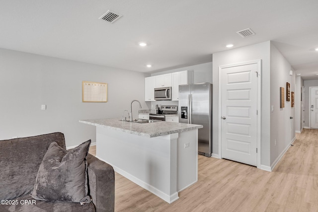 kitchen with a sink, light wood finished floors, visible vents, and stainless steel appliances