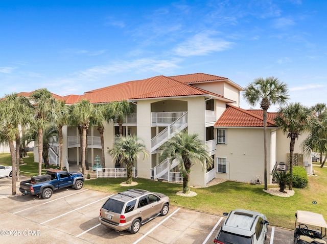 view of property featuring uncovered parking and stairway