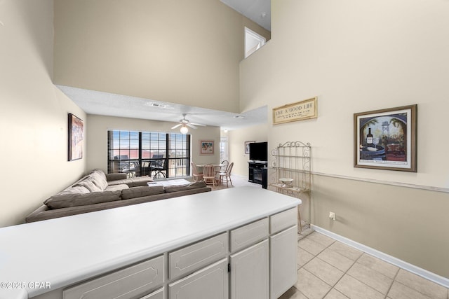 kitchen with light tile patterned floors, a ceiling fan, a high ceiling, and open floor plan