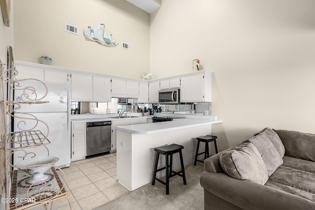 kitchen with a towering ceiling, visible vents, appliances with stainless steel finishes, and open floor plan