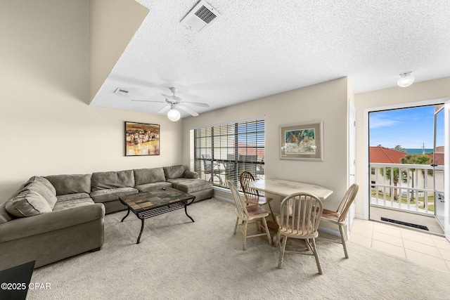 carpeted living area with a ceiling fan, visible vents, and a textured ceiling