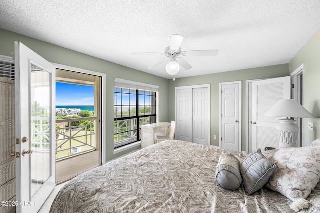 bedroom featuring access to exterior, a ceiling fan, a textured ceiling, and multiple closets