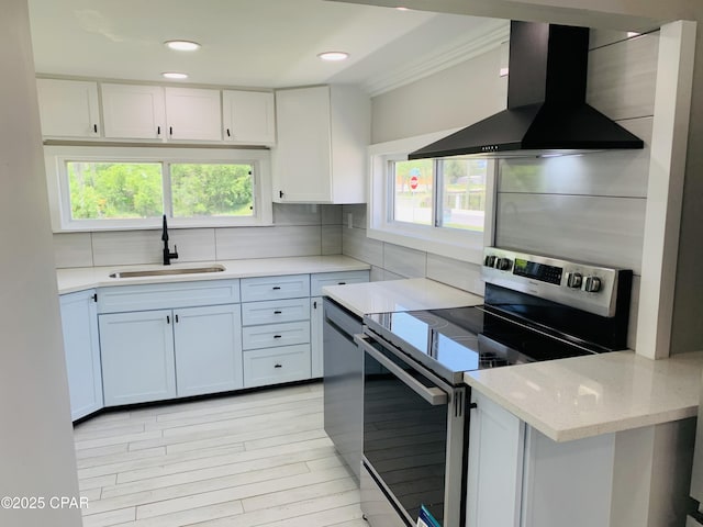 1003 E 8th St, Lynn Haven, FL 32444 - kitchen featuring wall chimney exhaust hood, a sink, white cabinetry, and stainless steel electric range