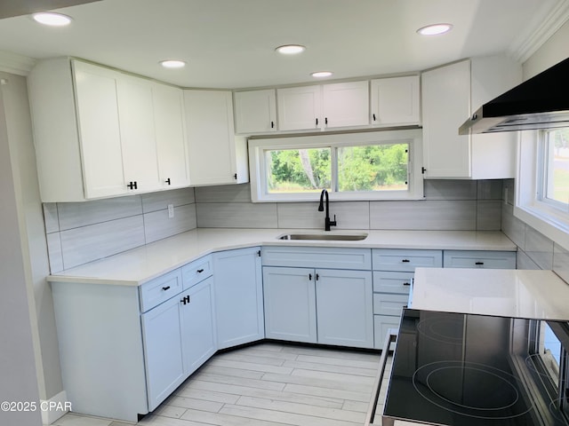 1003 E 8th St, Lynn Haven, FL 32444 - kitchen with recessed lighting, light countertops, wall chimney range hood, a sink, and white cabinetry