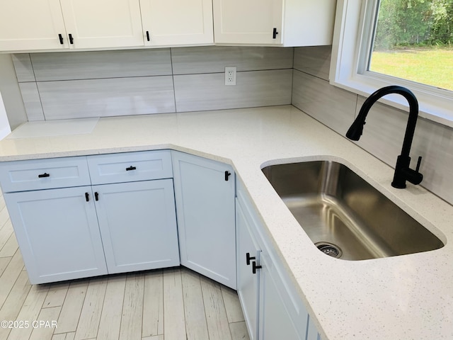1003 E 8th St, Lynn Haven, FL 32444 - kitchen with light stone counters, white cabinetry, decorative backsplash, and a sink