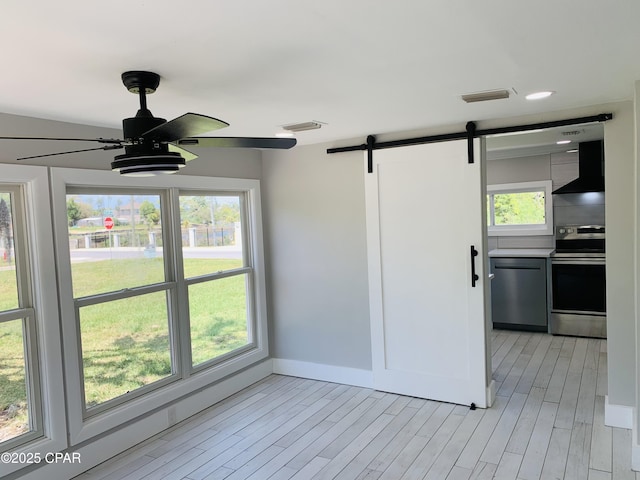 1003 E 8th St, Lynn Haven, FL 32444 - empty room with visible vents, a barn door, a ceiling fan, and a healthy amount of sunlight