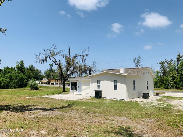 1003 E 8th St, Lynn Haven, FL 32444 - rear view of house with cooling unit, a lawn, and stucco siding