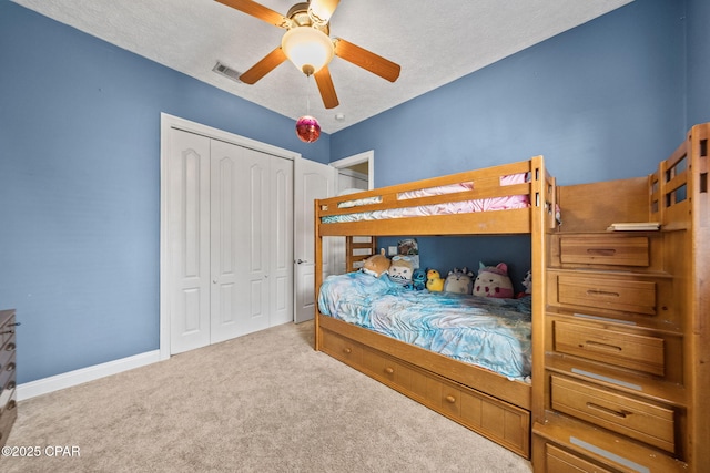 carpeted bedroom featuring a ceiling fan, a closet, a textured ceiling, and visible vents