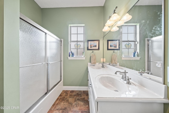bathroom featuring a sink, baseboards, enclosed tub / shower combo, and double vanity