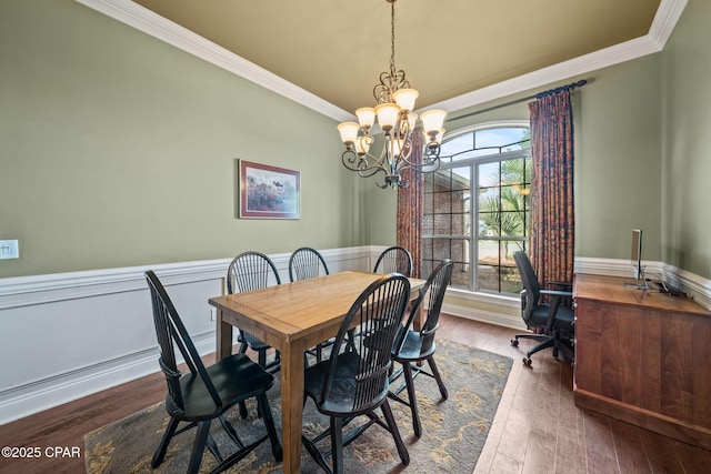 dining space featuring ornamental molding, wainscoting, a chandelier, and dark wood-style floors