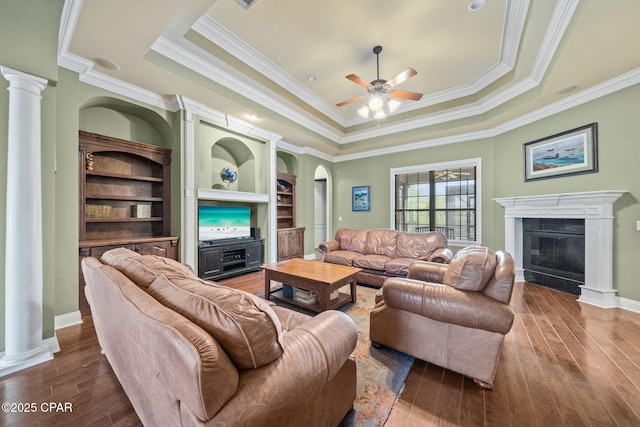 living area featuring ceiling fan, hardwood / wood-style flooring, ornamental molding, and a raised ceiling