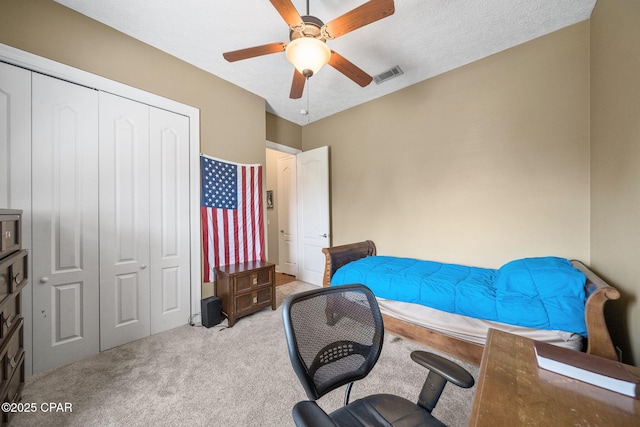 carpeted bedroom with ceiling fan, visible vents, and a closet