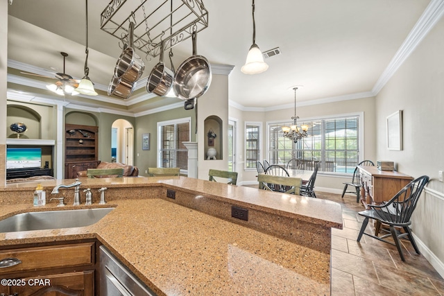 kitchen featuring decorative light fixtures, visible vents, arched walkways, a sink, and ornamental molding