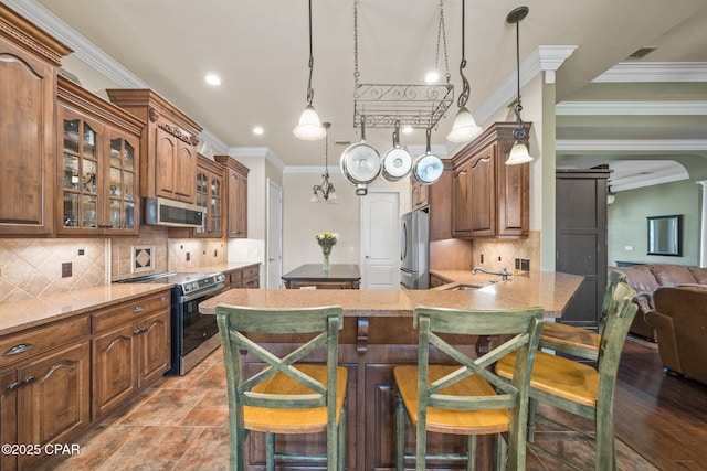 kitchen featuring crown molding, a sink, appliances with stainless steel finishes, and a kitchen bar