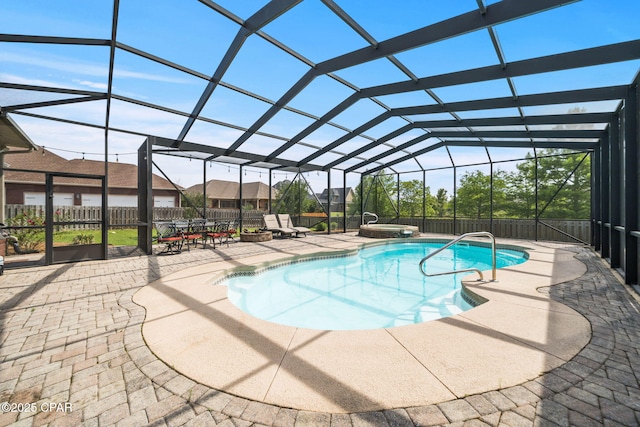 view of swimming pool with glass enclosure, a pool with connected hot tub, fence, and a patio area