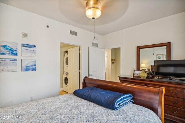 9900 S Thomas Dr Unit 1418, Panama City Beach, FL 32408 - bedroom featuring stacked washing maching and dryer, visible vents, and a ceiling fan