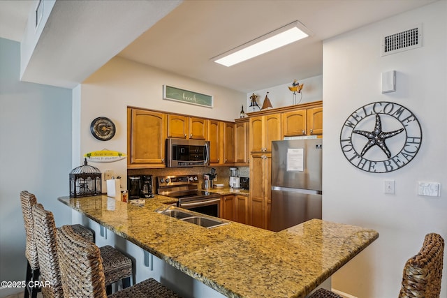 9900 S Thomas Dr Unit 1418, Panama City Beach, FL 32408 - kitchen featuring a breakfast bar area, visible vents, stainless steel appliances, and a peninsula