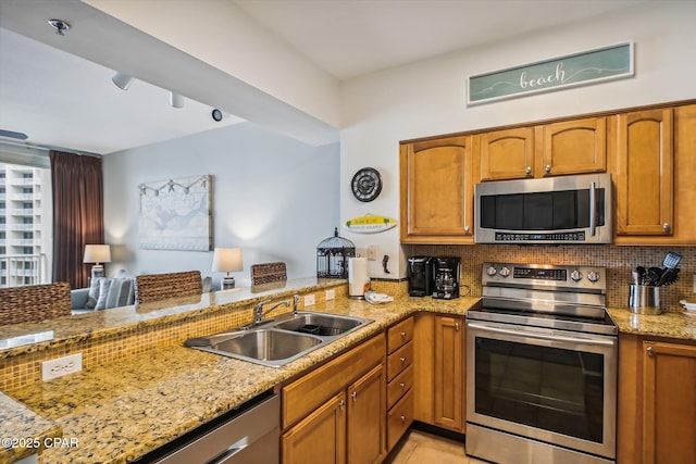 9900 S Thomas Dr Unit 1418, Panama City Beach, FL 32408 - kitchen with decorative backsplash, a sink, stainless steel appliances, light stone countertops, and brown cabinetry