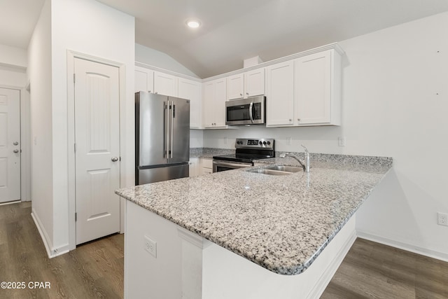 kitchen featuring a sink, dark wood finished floors, appliances with stainless steel finishes, and a peninsula