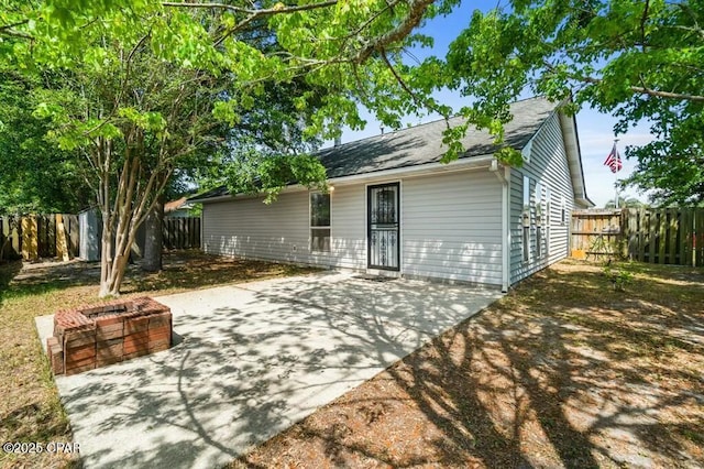 rear view of house featuring roof with shingles, a fenced backyard, and a patio area