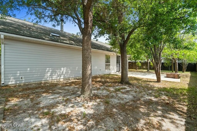 exterior space with fence, roof with shingles, and a patio area