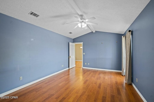 empty room with lofted ceiling with beams, a ceiling fan, visible vents, a textured ceiling, and wood finished floors