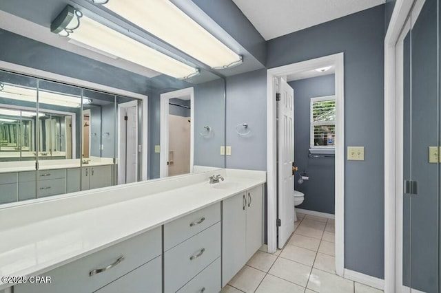 bathroom featuring baseboards, toilet, tile patterned flooring, and vanity