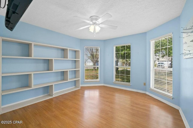 spare room featuring a textured ceiling, wood finished floors, and baseboards
